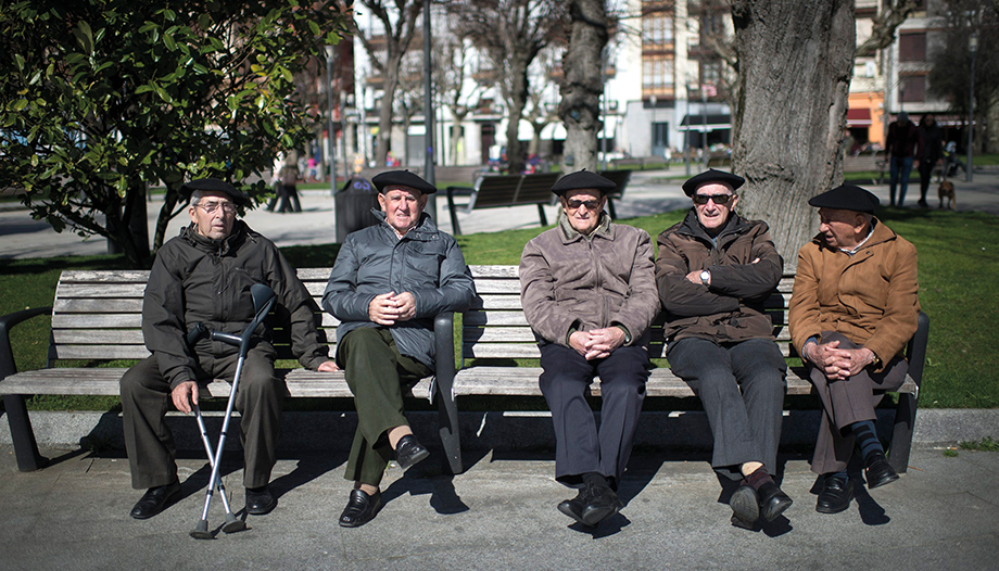 old people sitting on a bench in the street.