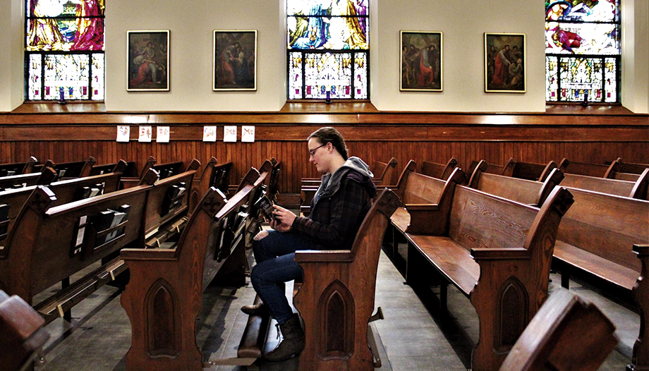 Jeune fille lisant un livre assise à l'intérieur d'une église.