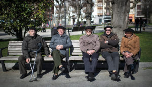 old people sitting on a bench in the street.