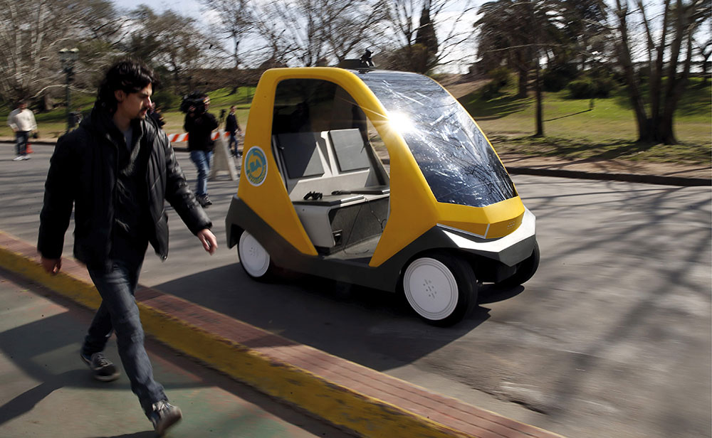 A man walks parallel to a prototype autonomous electric vehicle in Buenos Aires.