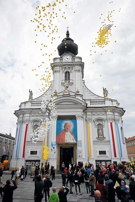 Grupa wiernych świętuje kanonizację Jana Pawła II przed kościołem parafialnym w Wadowicach.