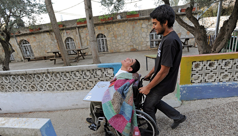 Un voluntario llevando a una persona con discapacidad en una silla de ruedas.